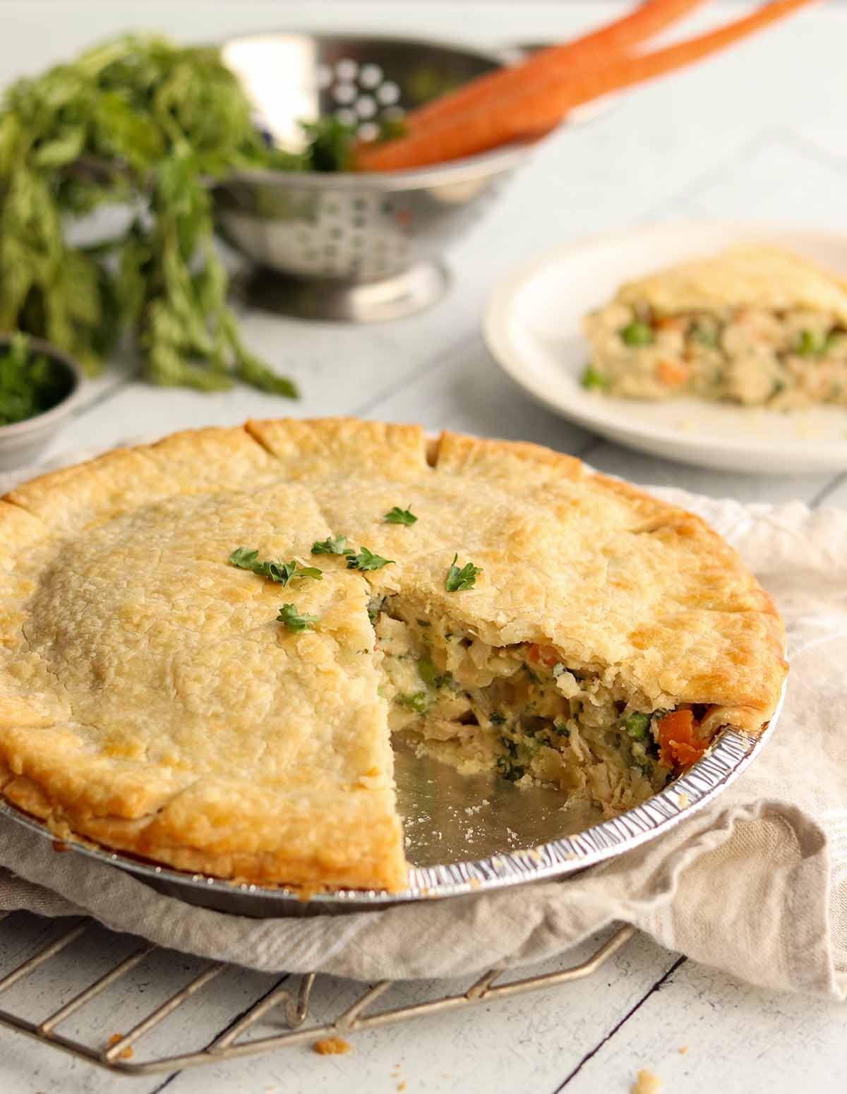 Whole gluten free dairy free chicken pot pie with slice missing exposing the tasty and colourful filling. topped with chives.