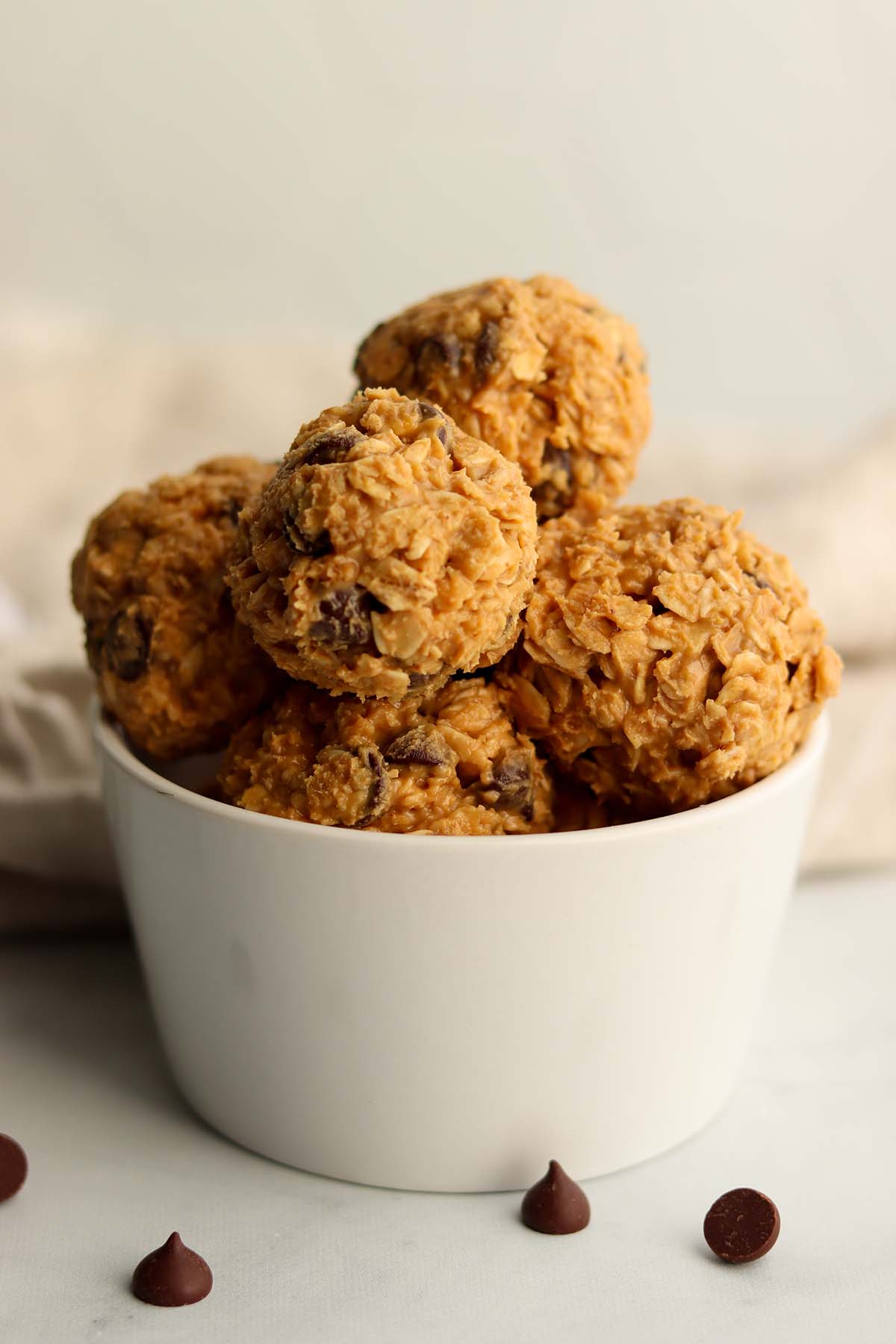 Close up view of edible cookie dough scooped into balls and placed in a white ceramic dish.