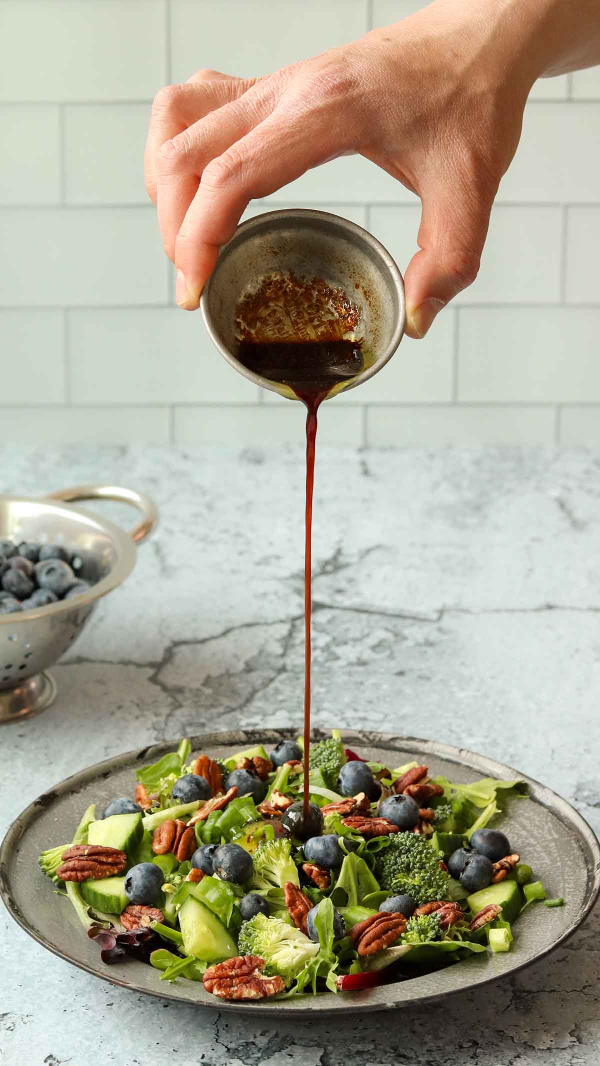 Vinaigrette being drizzled overtop of summer pecan salad