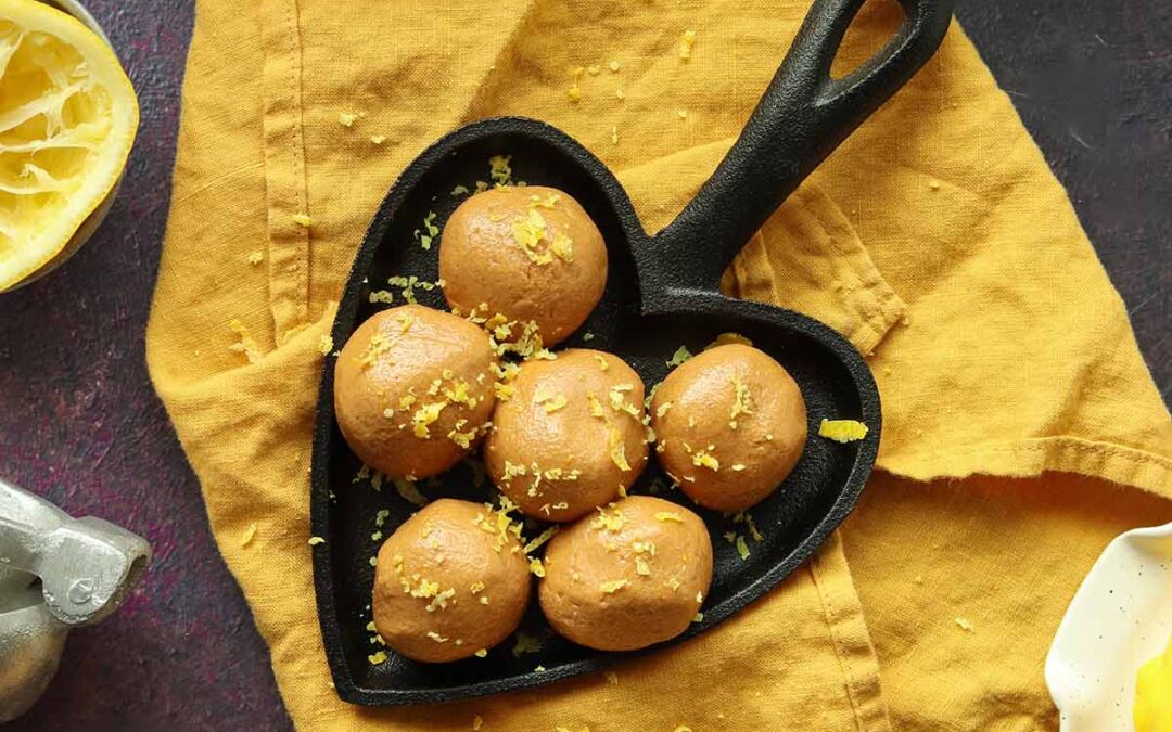 Zoomed out overhead view of collagen balls in a heart shaped cast iron skillet surrounded by ingredients and placed onto a yellow kitchen towel.