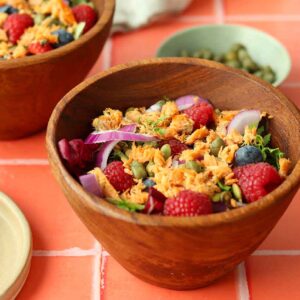 Side view of two wooden bowls with a colourful smoked salmon salad inside.